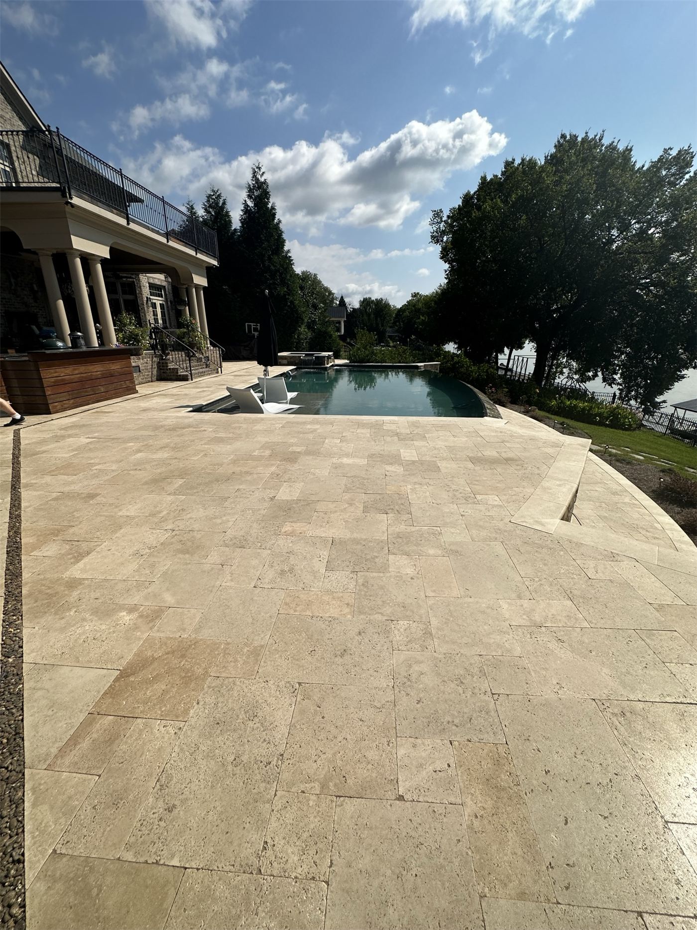 Sealed travertine pool deck beside an infinity pool
