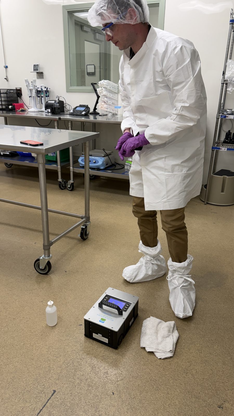 Technician in coveralls testing a floor inside a cleanroom