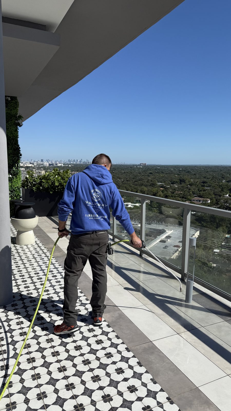 Technician slip testing a rooftop terrace with a city skyline behind